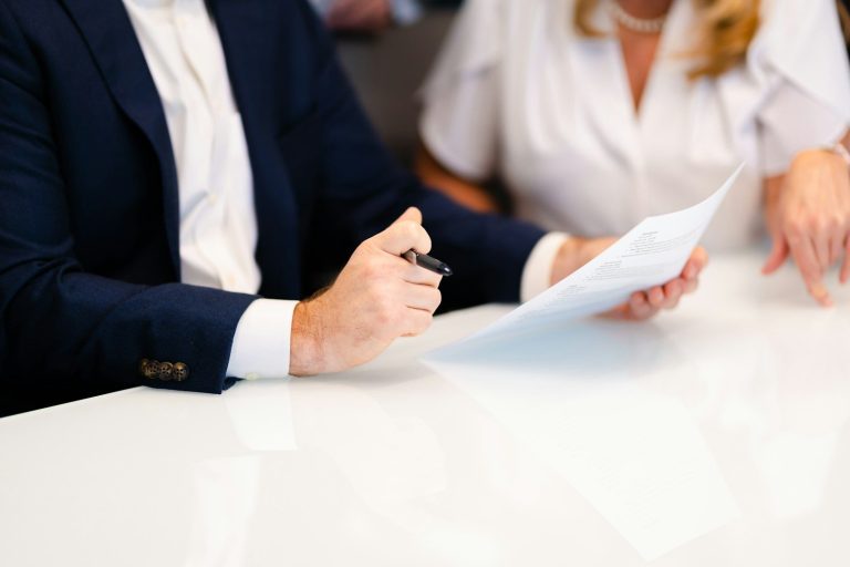 Two business people exchanging a document across a table.