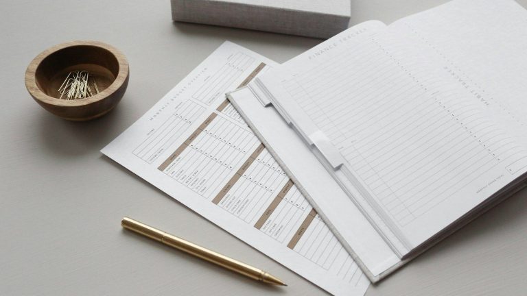 Printed forms and folders with a gold pen on a grey desk.
