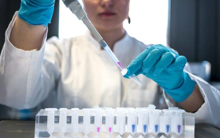 A scientist using a pipette with test tubes in a laboratory