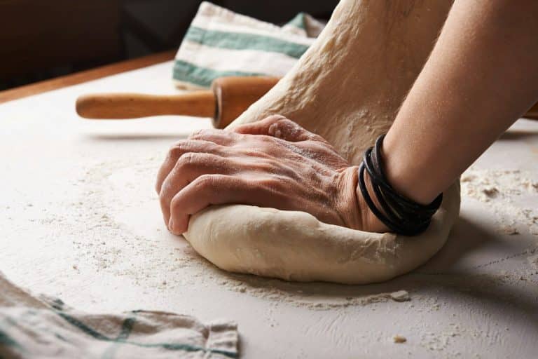 A person preparing dough beside a rolling pin