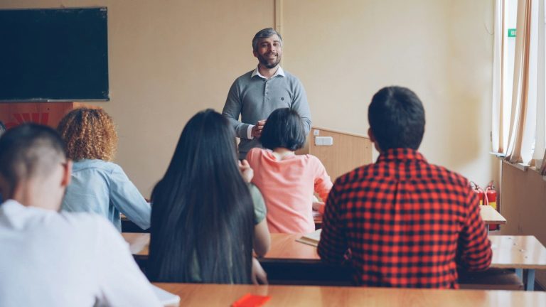 A presenter speaks to a seated group of employees in a training session.