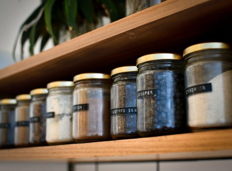 Containers on a wooden shelf with small labels identifying their contents.