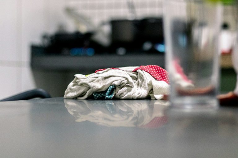 A cloth resting on a clean stainless steel kitchen bench.