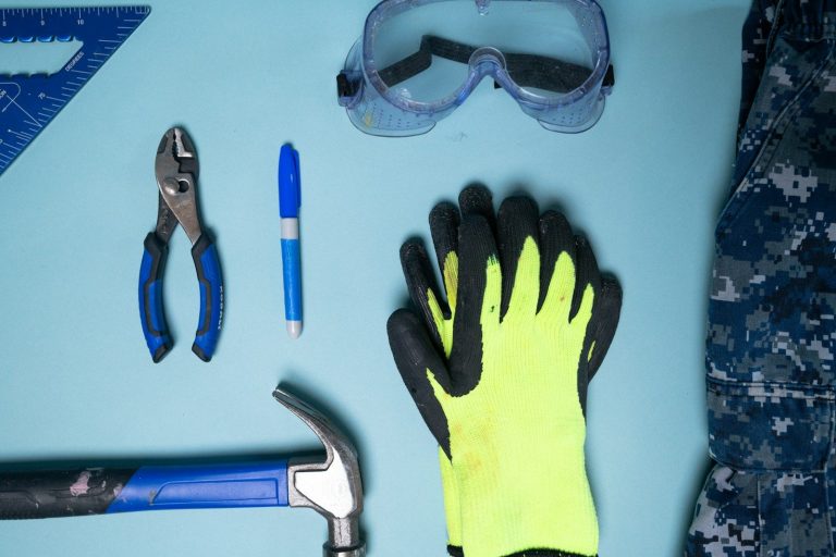 Safety goggles and protective gloves laid out on a bench beside a marker pen.