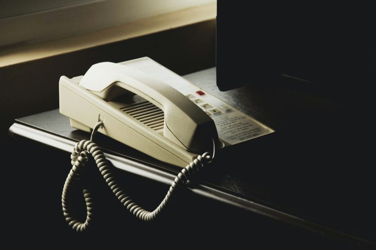 Cream desk telephone with a coiled cord on a dark desk