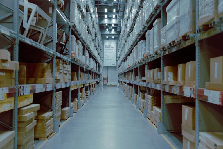 A long aisle of warehouse shelving stacked with boxed goods in a storage facility.