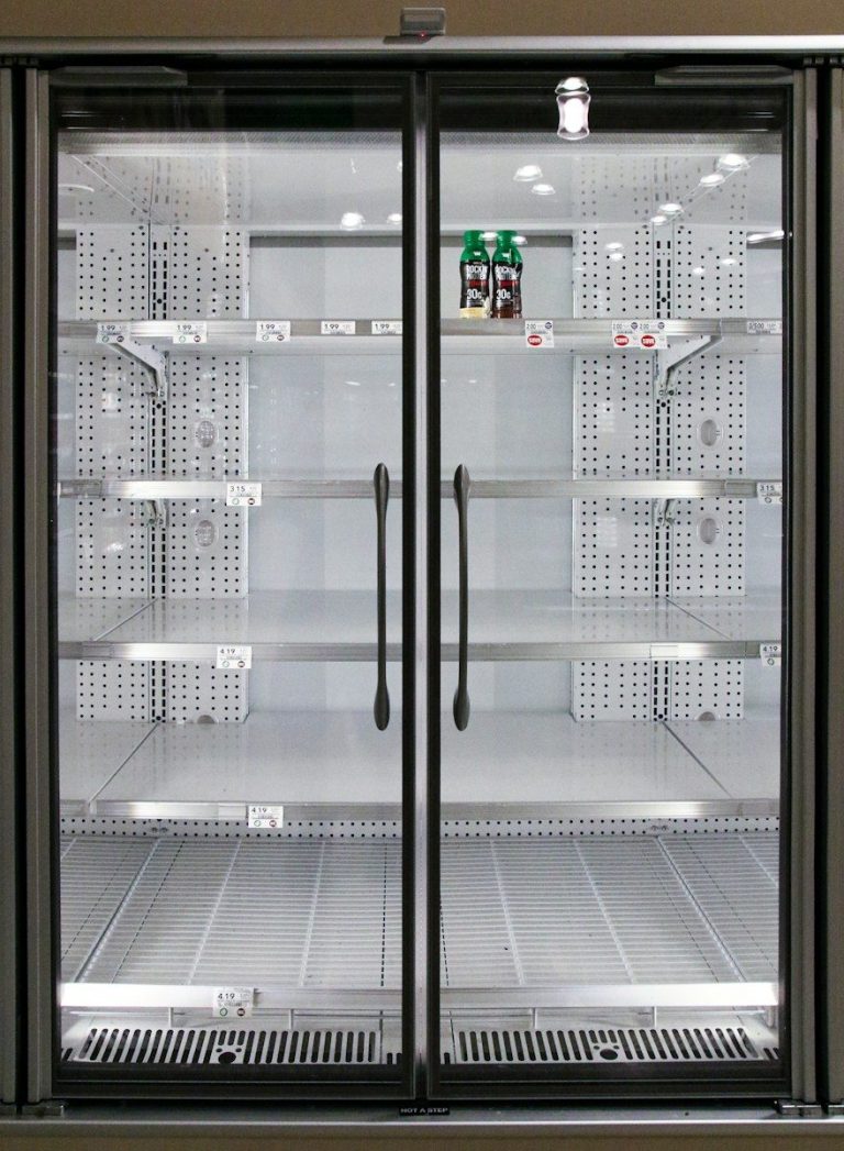 A clean, empty commercial double door refrigerator with glass doors and stainless steel shelving.