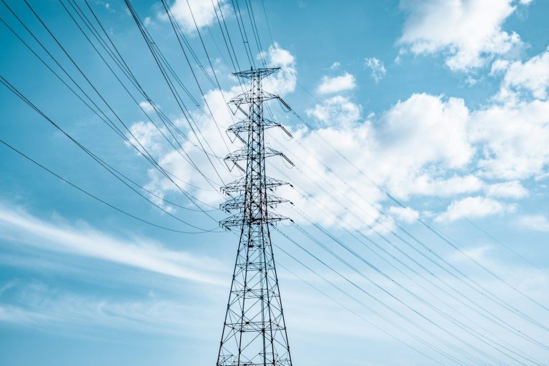 High voltage electricity pylon against a blue sky with clouds