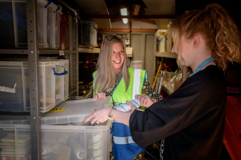 A worker in a high visibility vest checking stored containers in a storage area.