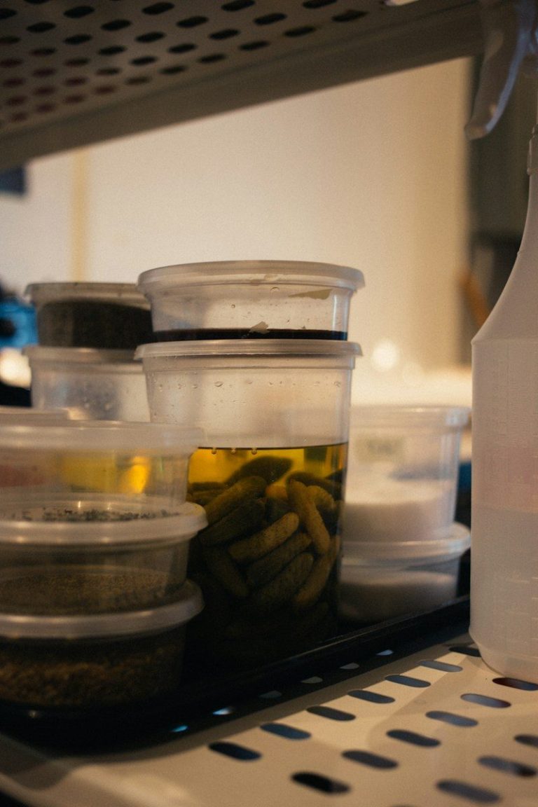 Clear plastic containers stacked on a shelf holding prepared food in a storage area.