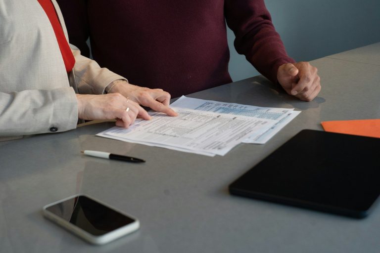 Two people reviewing printed contract pages together at a table.