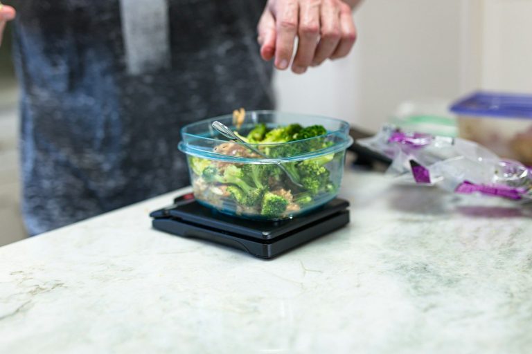A container of fresh salad on a digital scale being weighed on a kitchen bench.