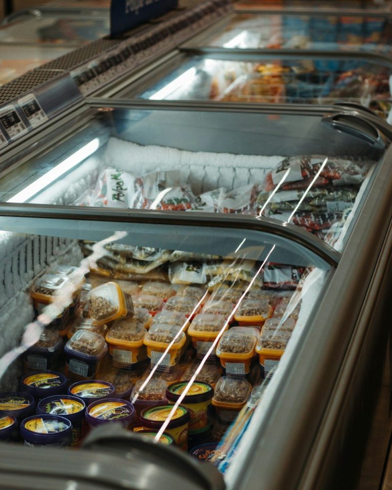 An open chilled display cabinet holding packaged foods under cold storage conditions.