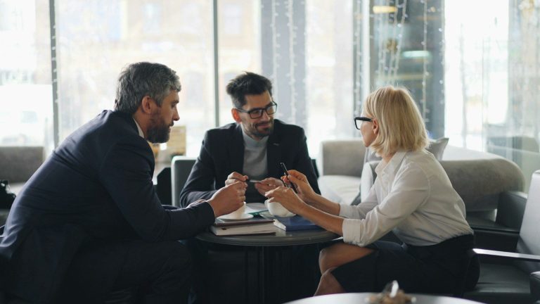 A group of business colleagues talk around a meeting table.