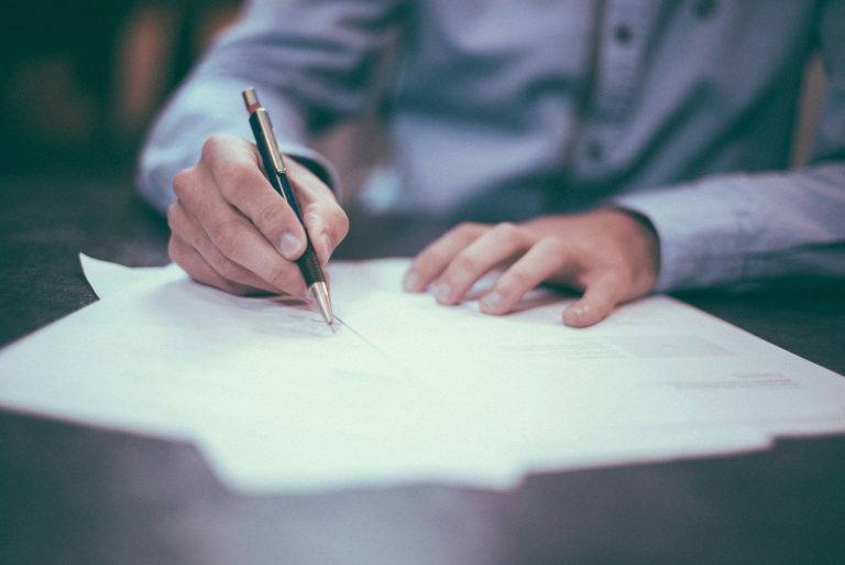 Person signing a document on a desk