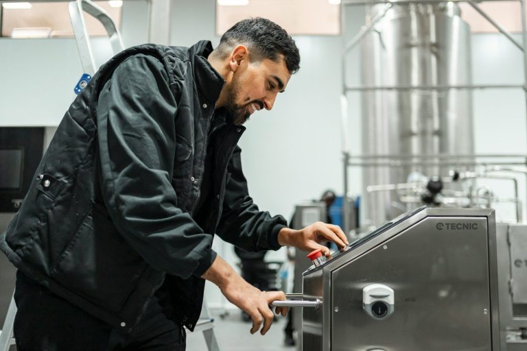 A food technician adjusting the controls on a processing machine in a factory.