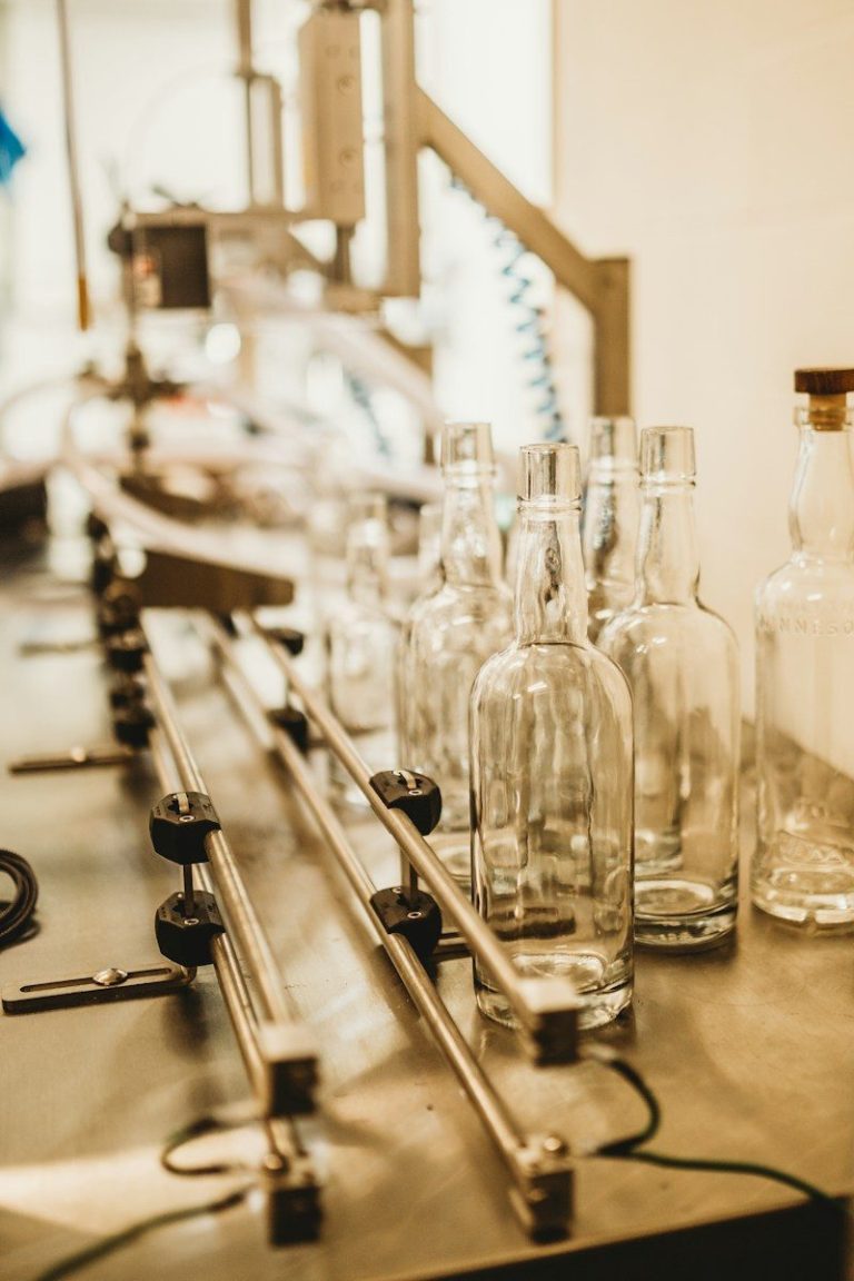 Empty glass bottles move along a conveyor on a packaging line.
