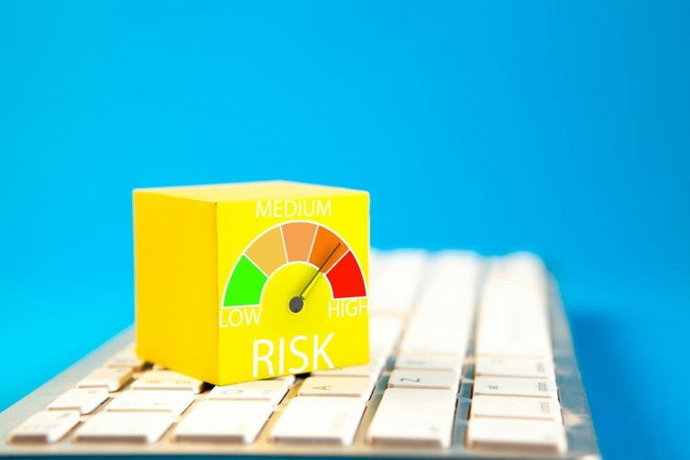 Yellow cube with a risk gauge pointing between medium and high on a keyboard