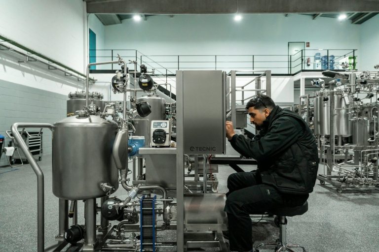 A technician working on the controls of a large stainless steel processing machine.