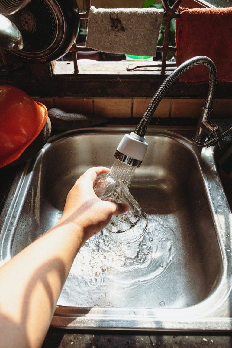 A person washes their hands under a running tap.