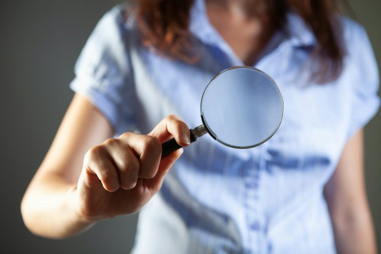 Person holding a magnifying glass to examine something closely