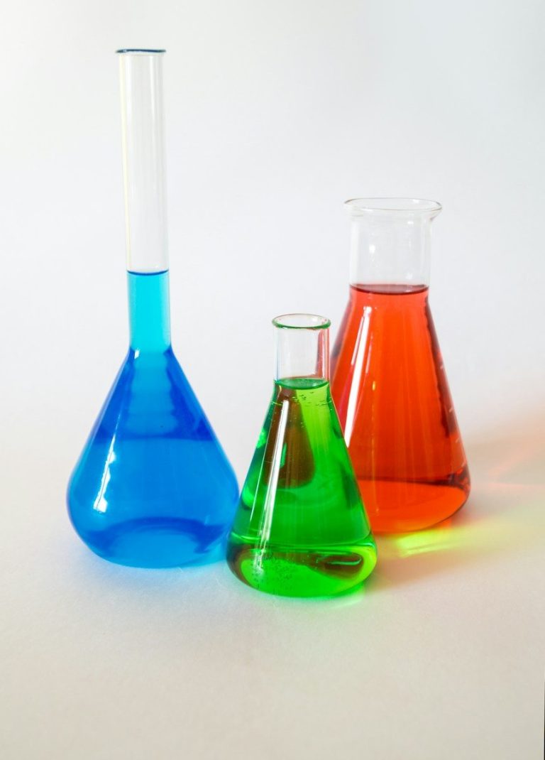 Laboratory flasks holding blue, green, and orange solutions