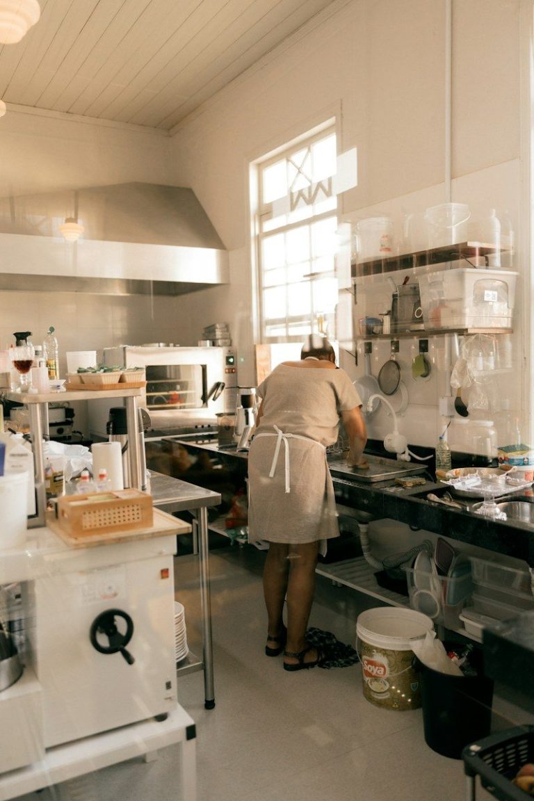 A cook working at a bench in a commercial kitchen preparing food.